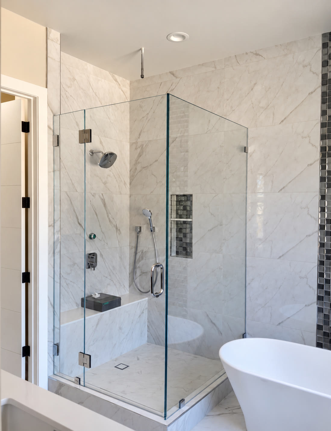 Glass-enclosed shower with stone-look tile and chrome fittings