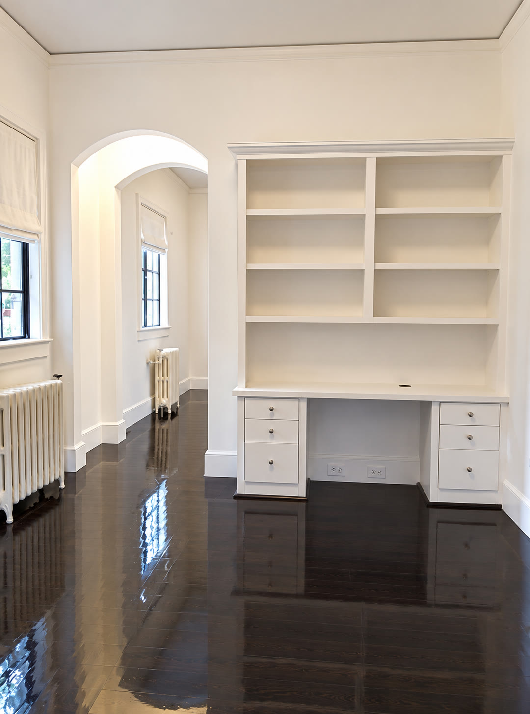 Custom white built-in desk and shelving with dark floors