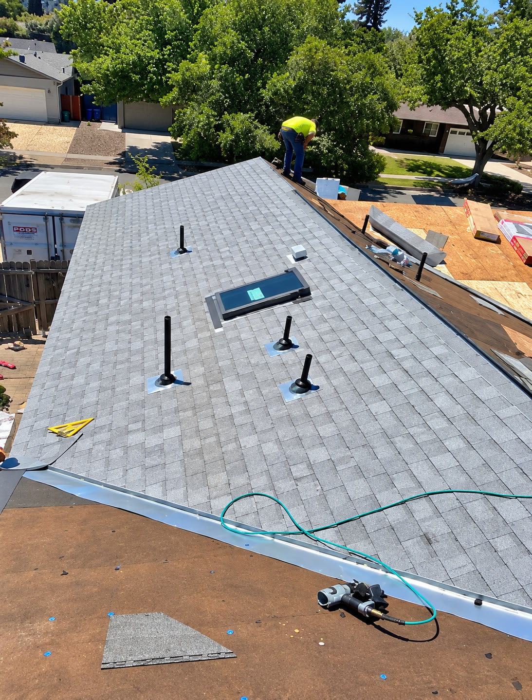 Roof installation with shingles, skylight and plumbing vents