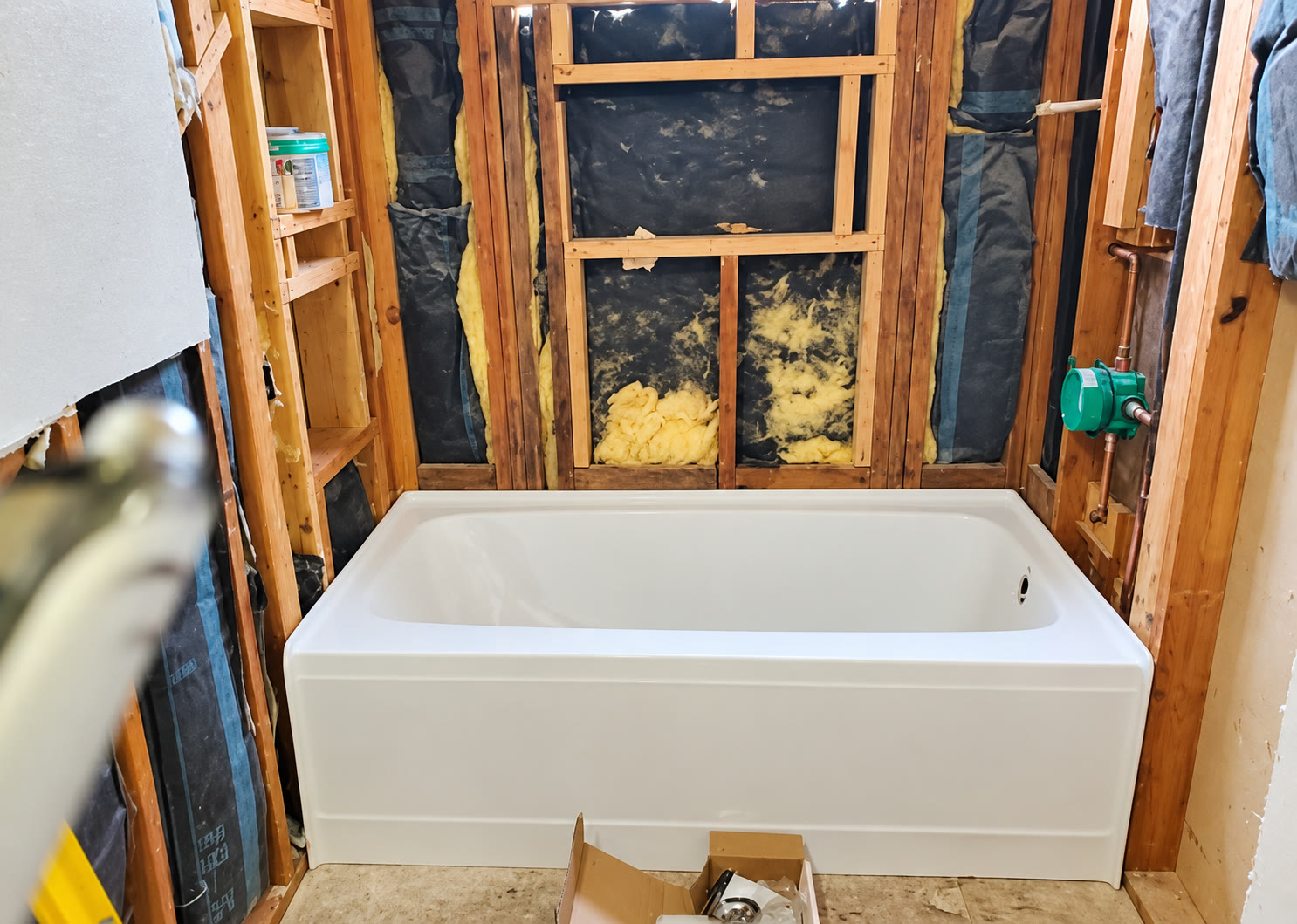 Bathtub installation with exposed plumbing and wall studs