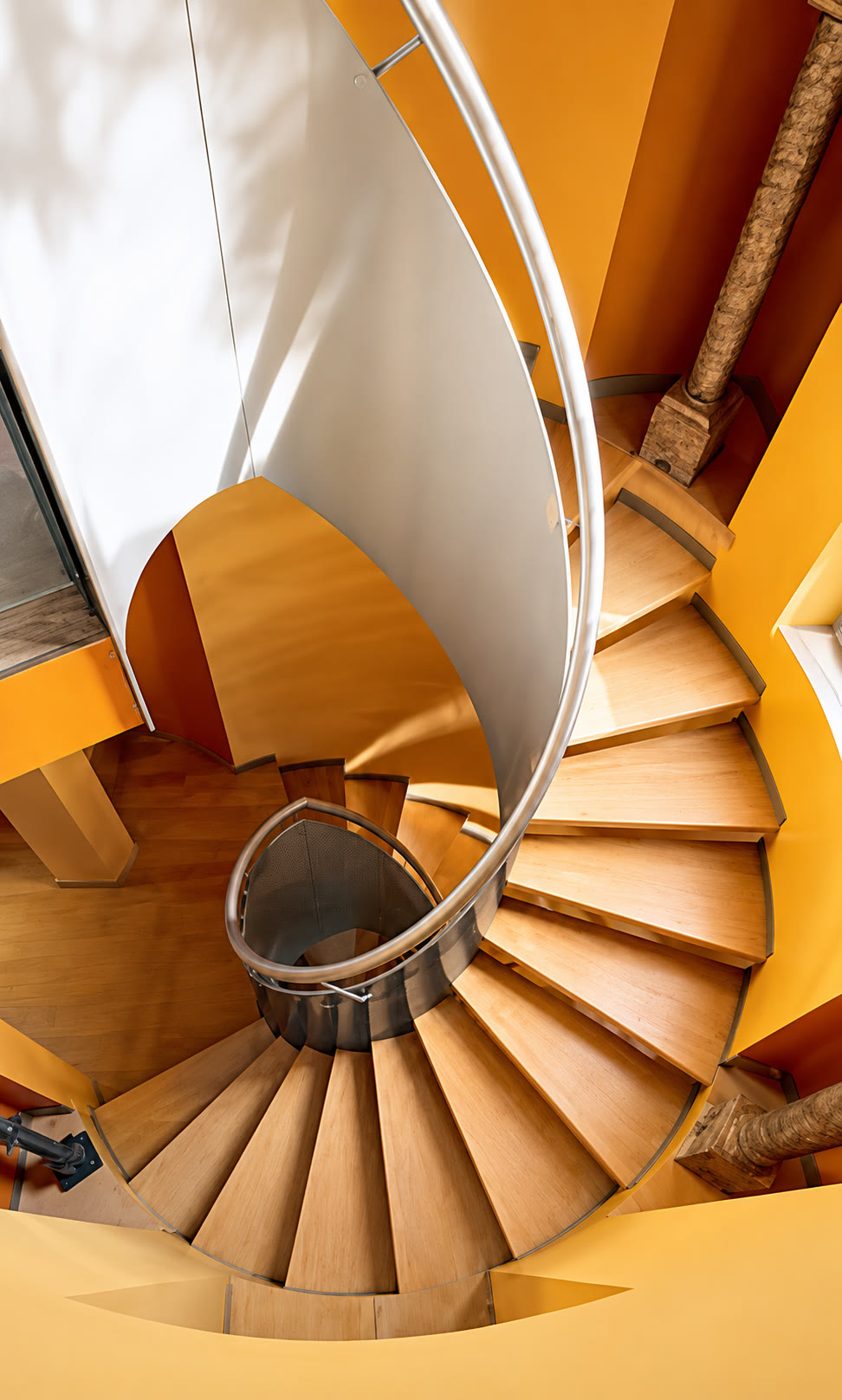 Spiral staircase with curved metal railing and wood treads