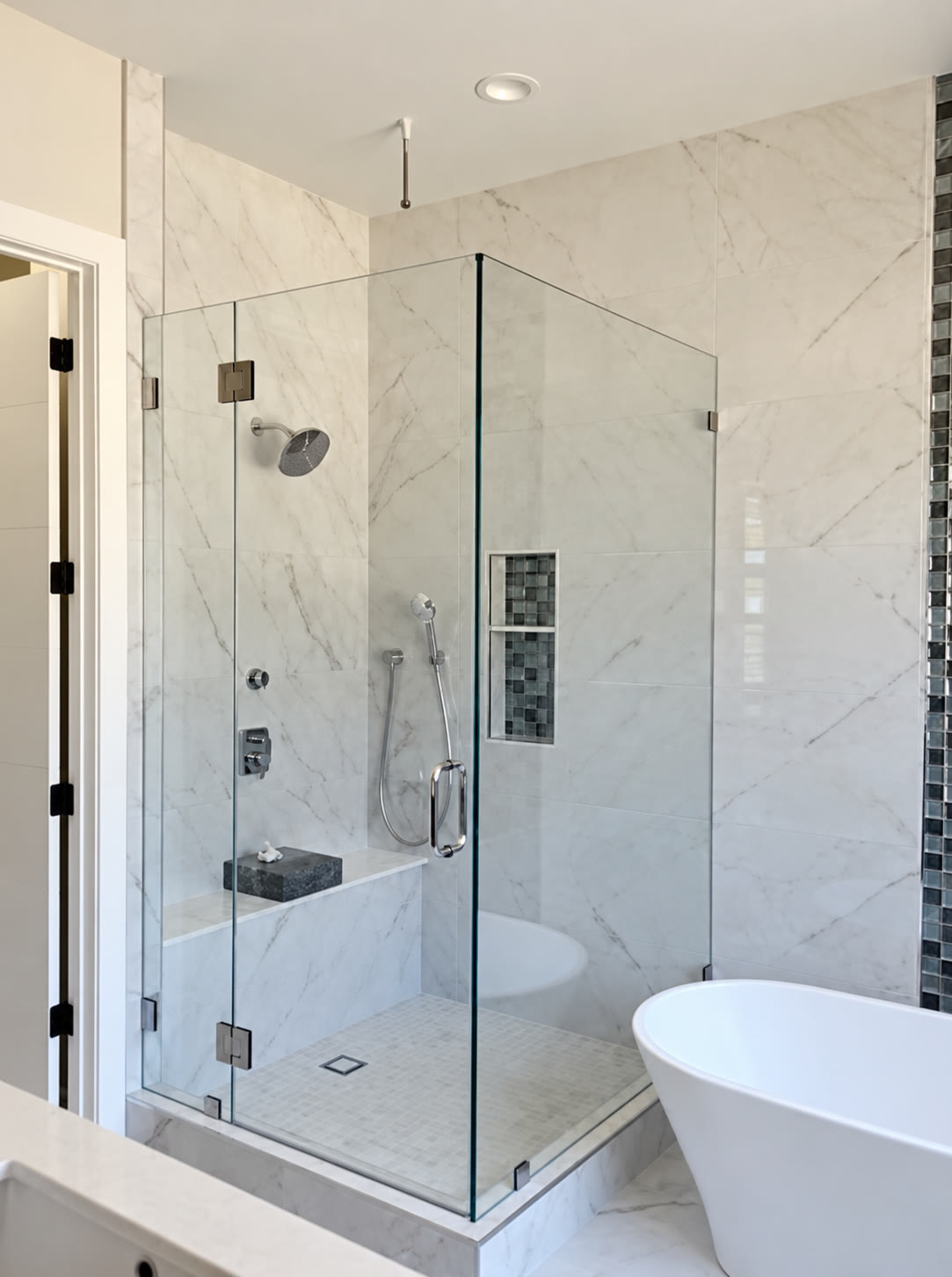 Alternate view of a tiled glass-enclosed shower and bathtub